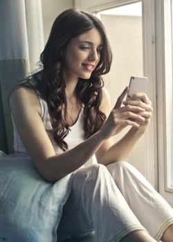 woman-sitting-beside-window-holding-phone